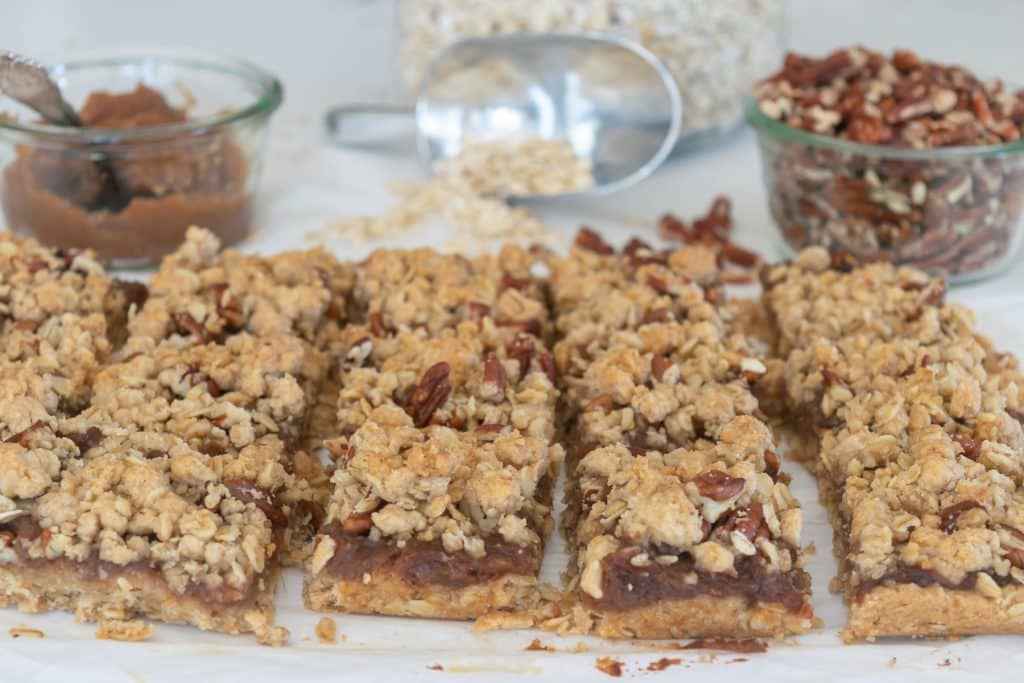 Cut apple butter bars with oats in a scoop in the background.