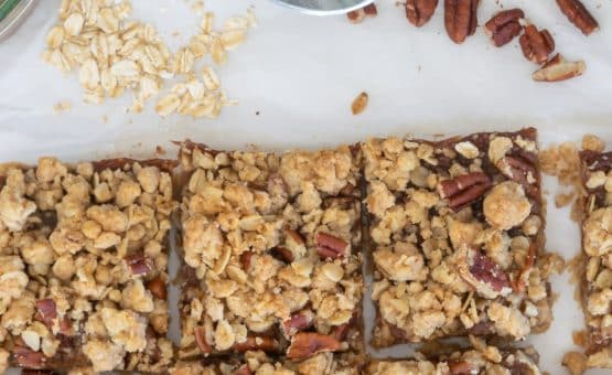 Apple Butter Oatmeal Bars with spinkled rolled oats and pecans in the background.