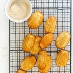 Spiced Madeleines on a cooling rack with a bowl of maple glaze.