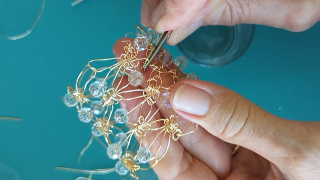 Using tweezers to secure the ends of the wire macrame.