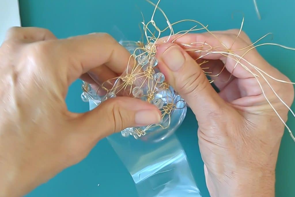 Use tape to secure the wire macrame around the glass votive while you bend the wire ends.