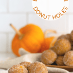 Three pumpkin spice donut holes on a wooden plate.