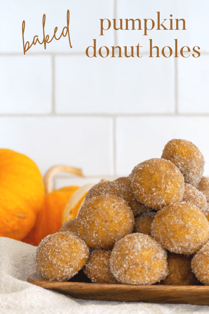 Stack of Baked Pumpkin Donut Holes on a wooden tray.