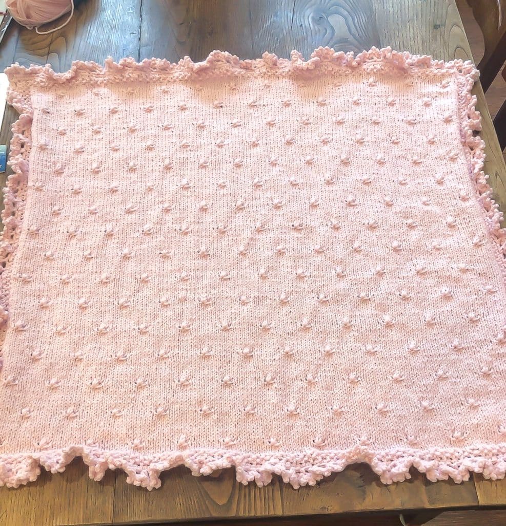Rosebuds and ruffles baby blanket on wooden table.