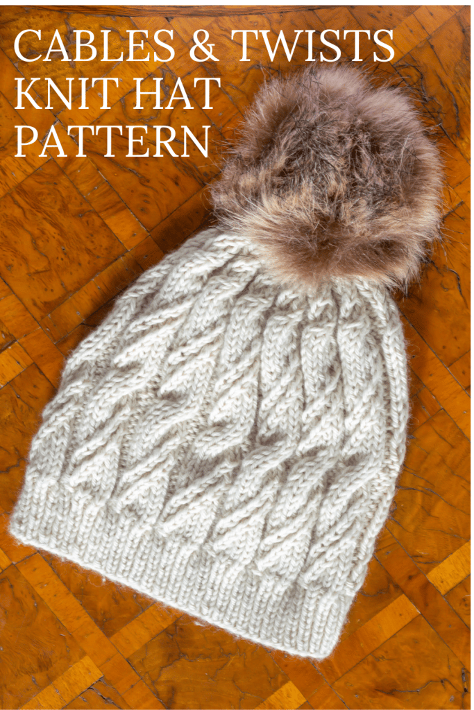 Hat knit using this Twists and Cable Knit Hat Pattern on wood surface.