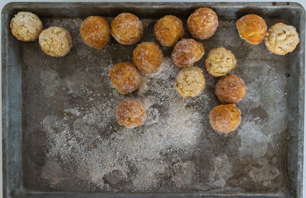 shake pan back and forth to cover doughnuts with sugar.