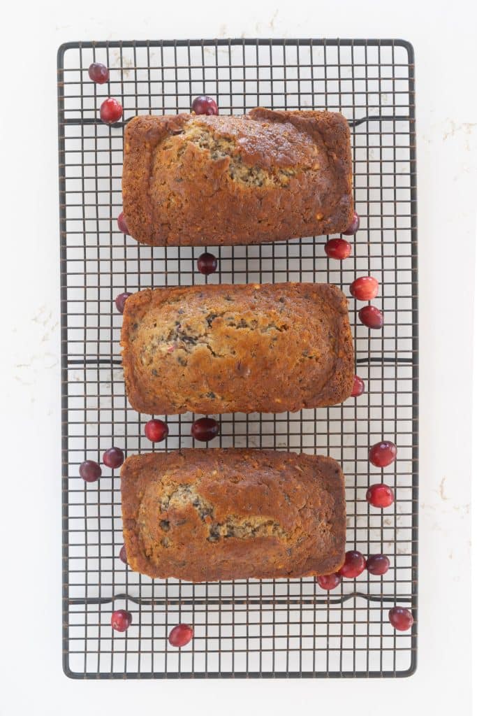 Cranberry, Apple and Banana Bread on a cooling rack with scattered cranberries.