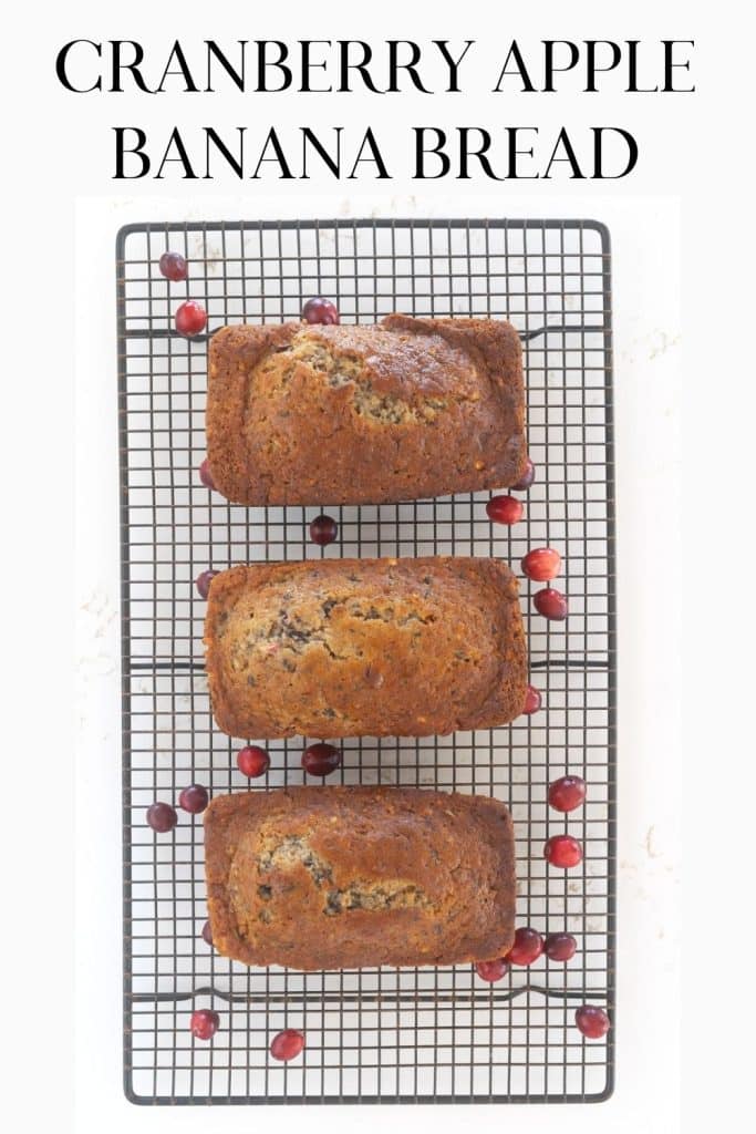 Cranberry Apple and Banana Bread on a cooling rack with cranberries sprinkled around.