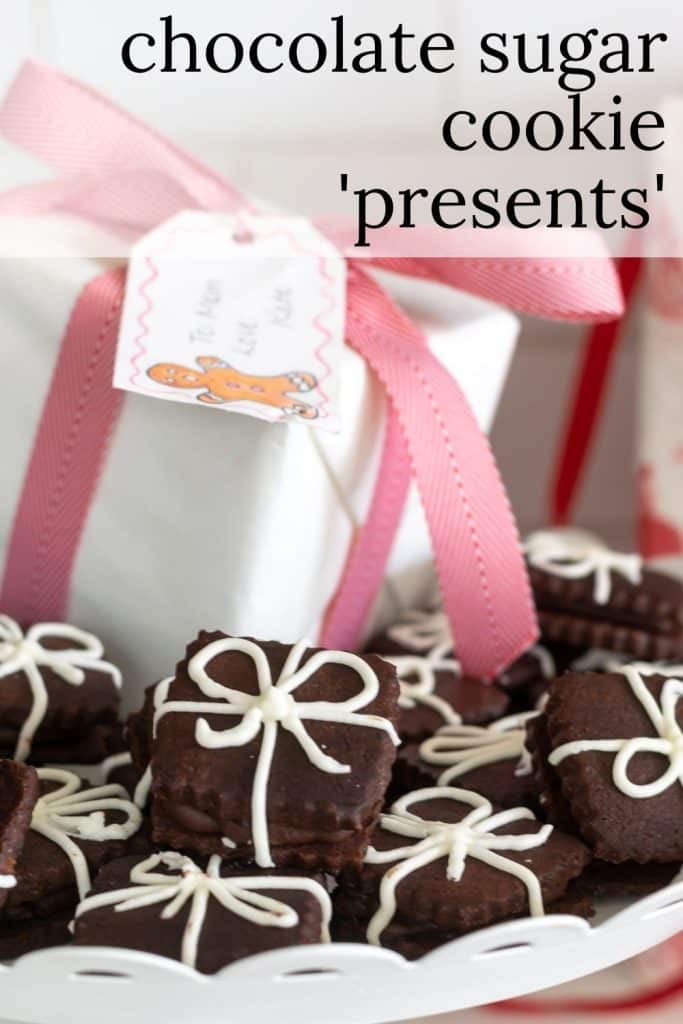 Chocolate Sandwich cookies with icing that looks like a ribbon and a white box wrapped in pink ribbon.