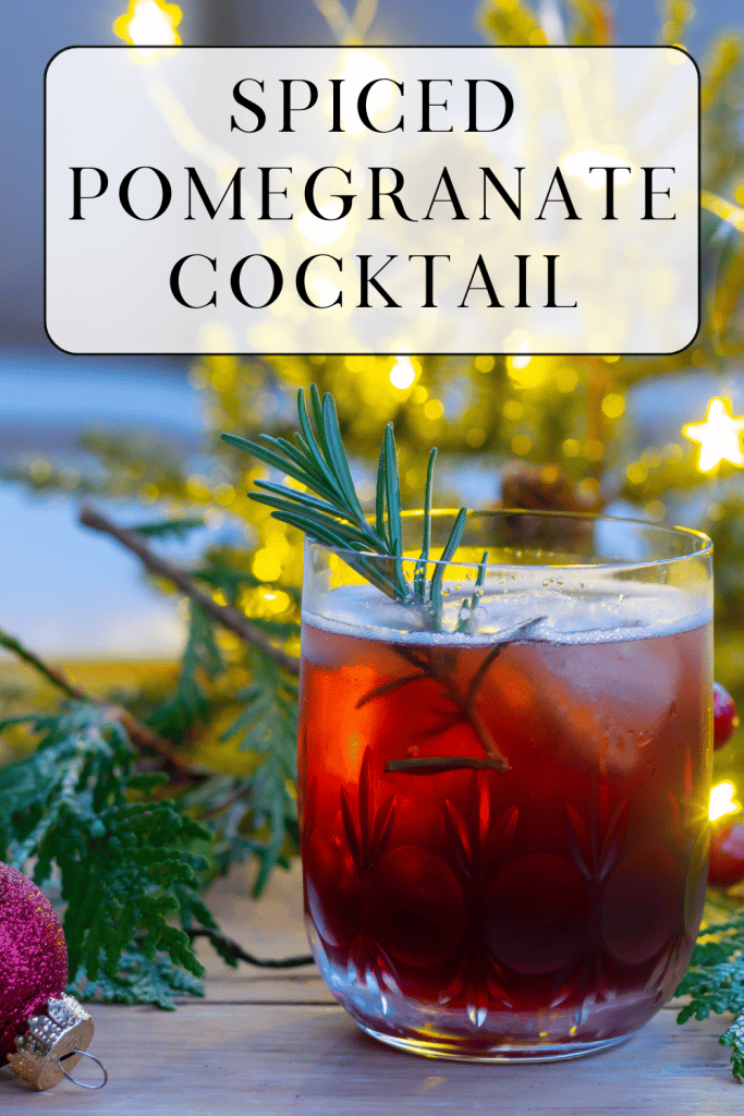 Spiced Pomegranate Cocktail in front of a lit Christmas tree.