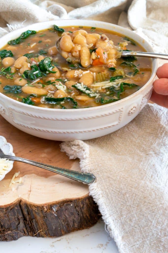 A bowl of Tuscan White Bean Soup with a spoon.