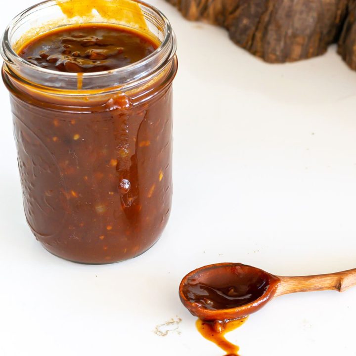 Jar and wooden spoon with barbecue sauce.