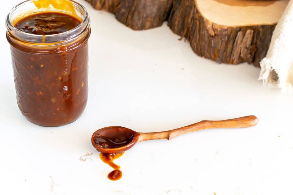 BBq sauce in a jar with a wooden spoon.
