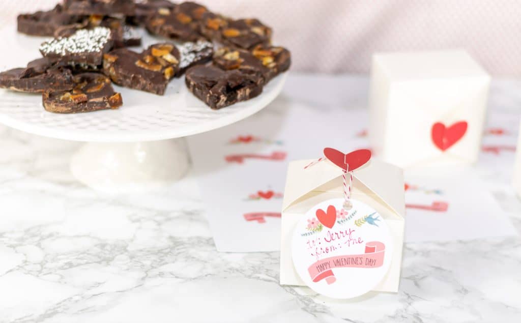 Valentine's Day Chocolate Bark on a white plate with gift boxes.