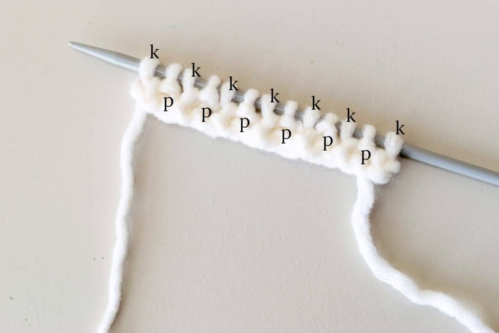 Stitches on knitting needle with letter K and P showing Knit and Purls.