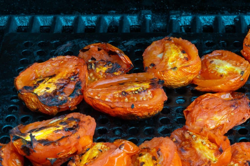 Tomatoes roasting on a grill.