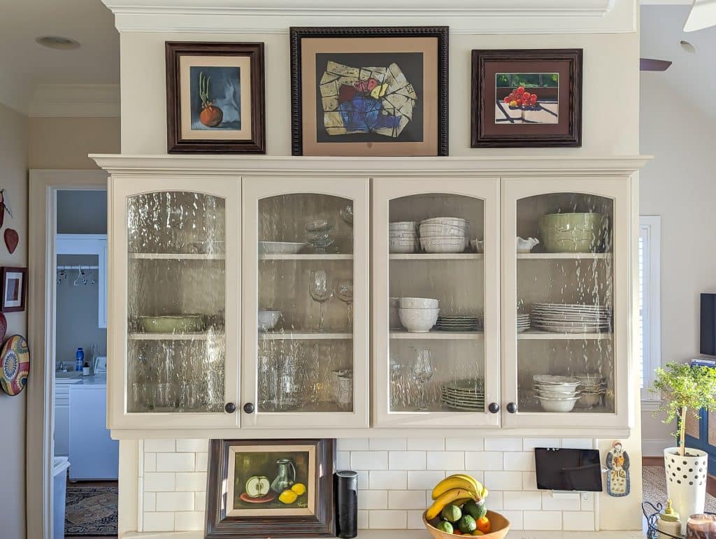Kitchen cabinets with paintings over the cabinets.