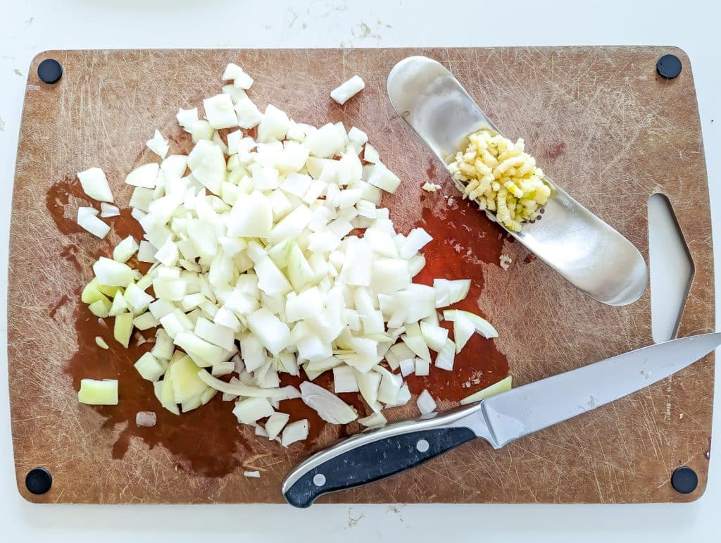 Diced onion and garlic on a cutting board.