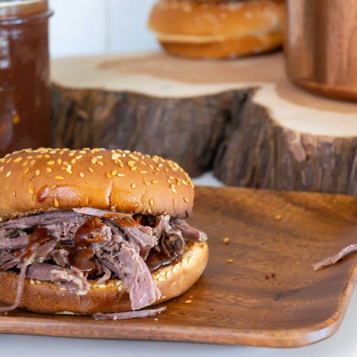 A bbq sandwich sitting on top of a wooden plate.