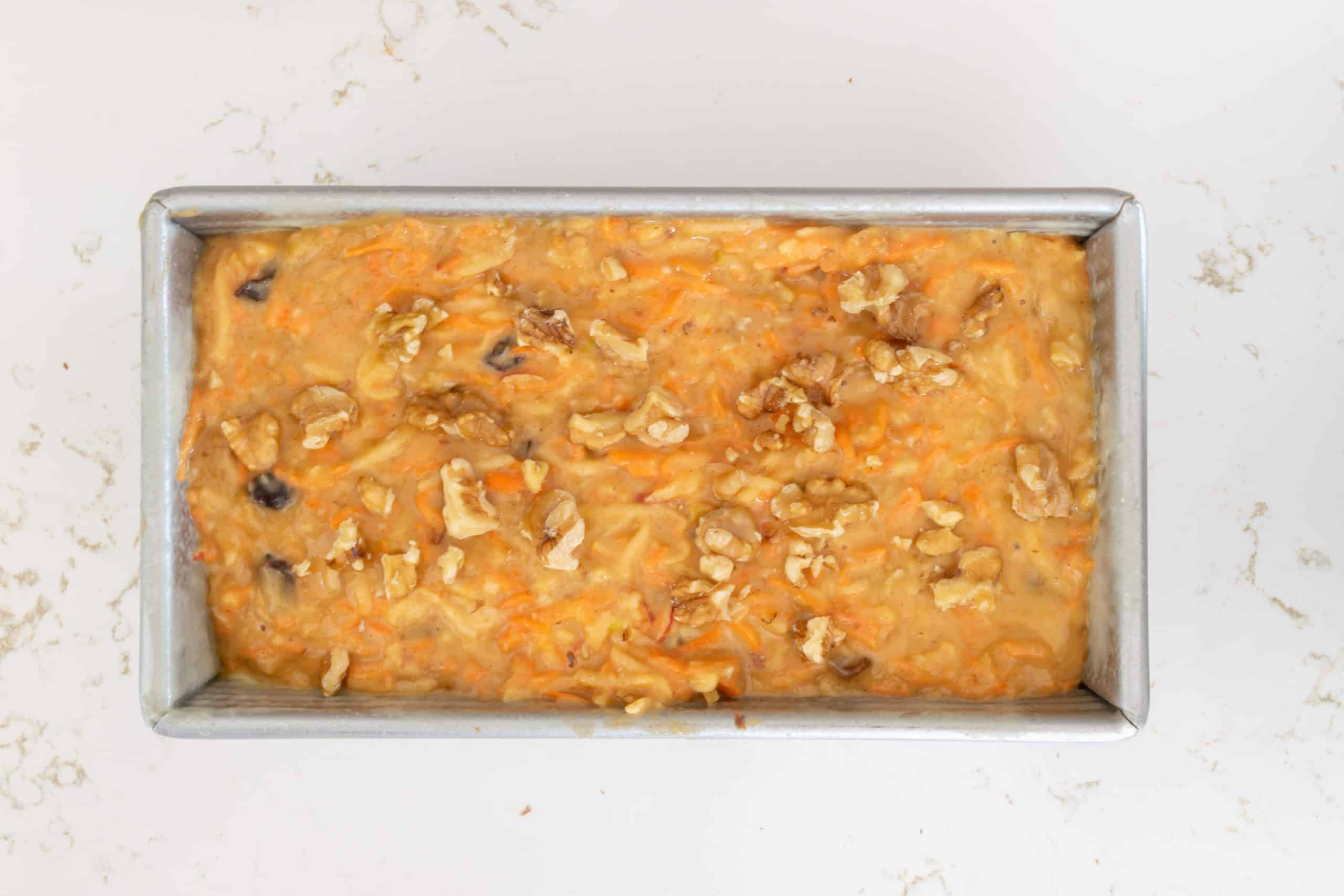 Bread batter in loaf pan, sprinkled with walnuts.