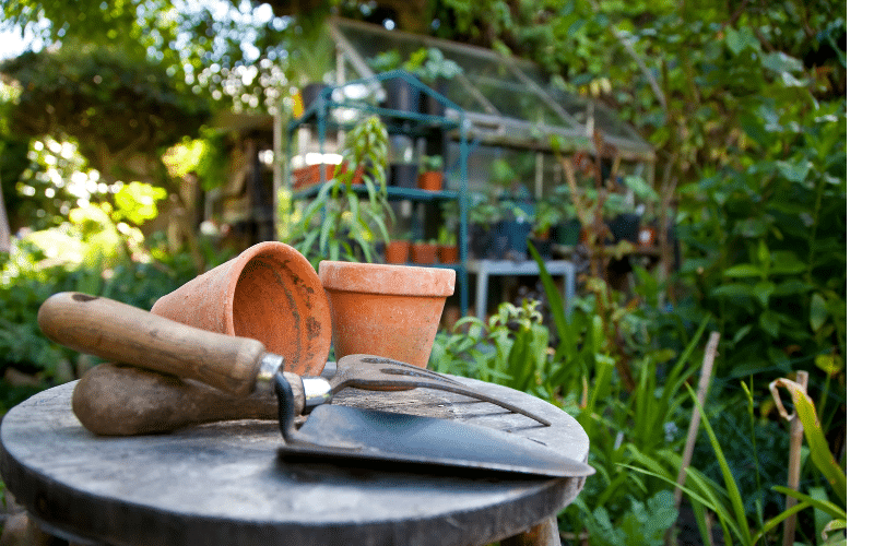 Small shovel, cultivator and pots on a stool.
