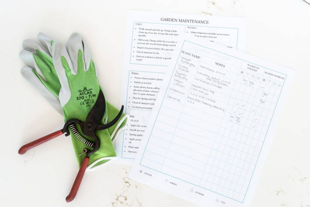 Green and white garden gloves with hand trimmers and two sheets of paper, one detailing daily, weekly and seasonal garden maintenance, and the other details the fertilization and pruning needs of your plants.