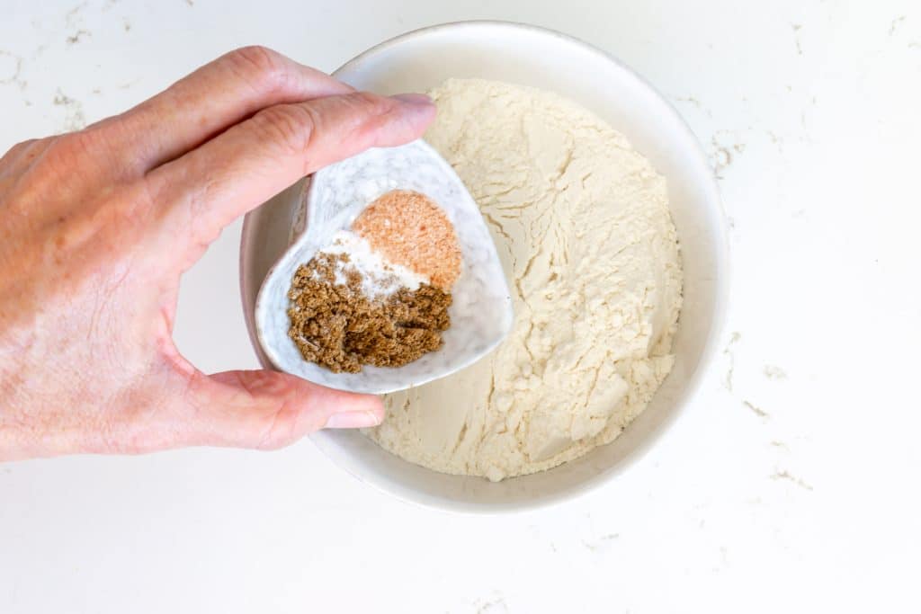 Adding salt, baking powder, and cardamom to flour.