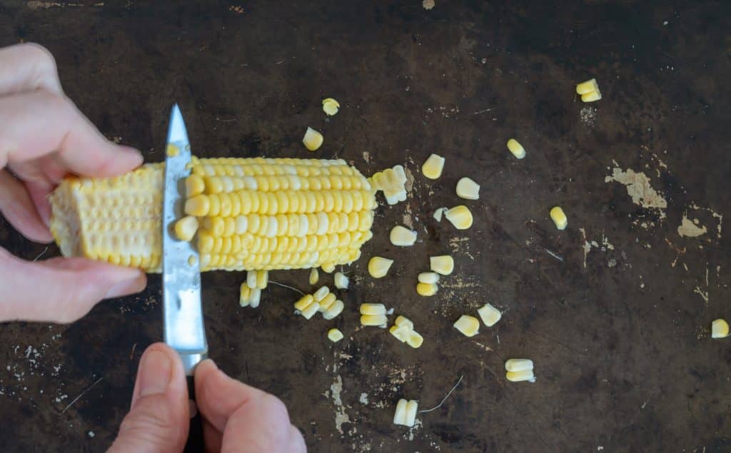 Cutting corn off of the cob.