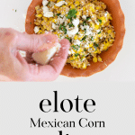 Hand crumbling cotija cheese over a bowl of elote dip.
