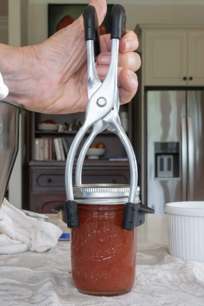 Use a jar lifter to transfer jar to simmering pot of water.