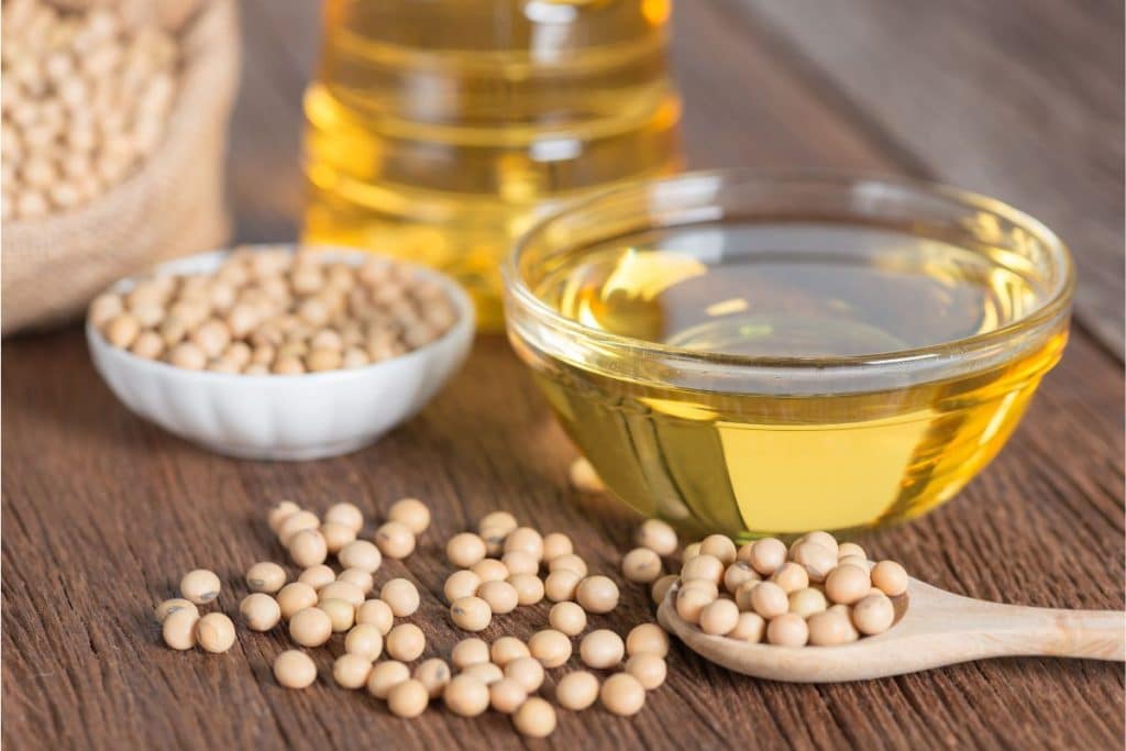 Soybeans and soybean oil in clear glass bowls.