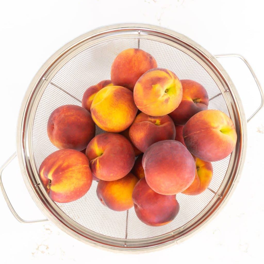 Colander of fresh peaches.