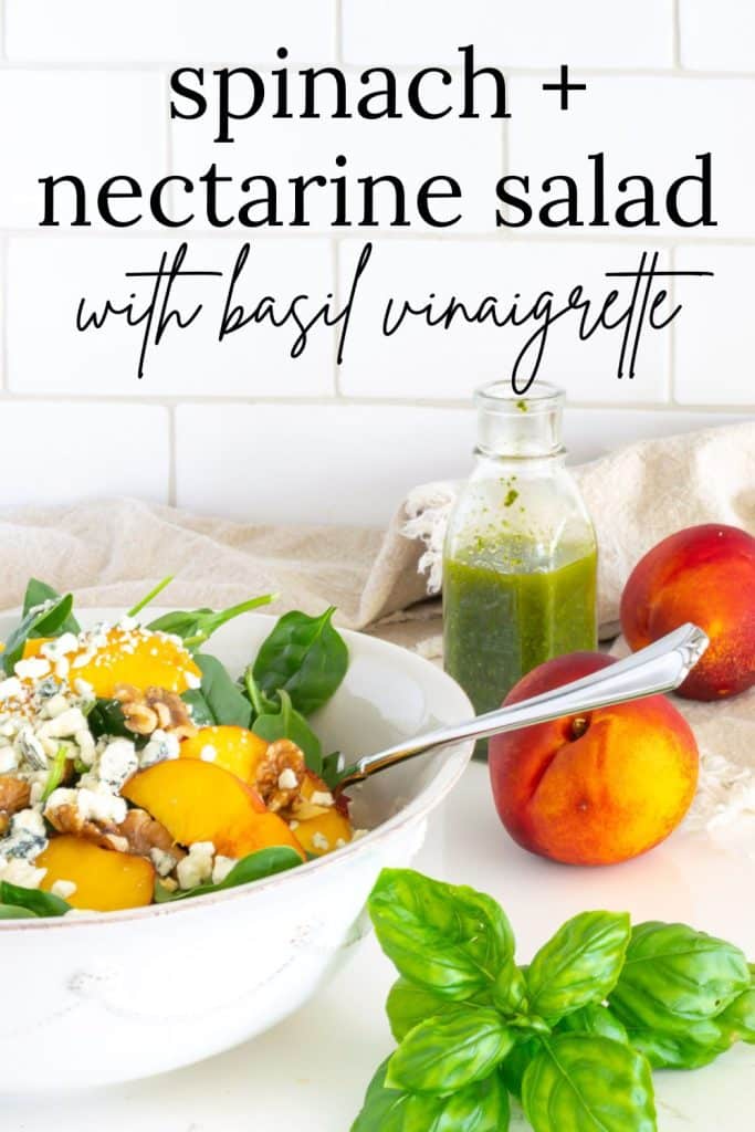 Spinach and Nectarine Salad in a white bowl with nectarines, basil and basil vinaigrette in the background.