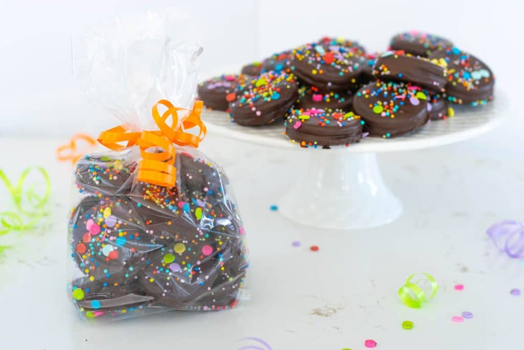 Chocolate Covered Oreos in a bag with ribbon and confetti.
