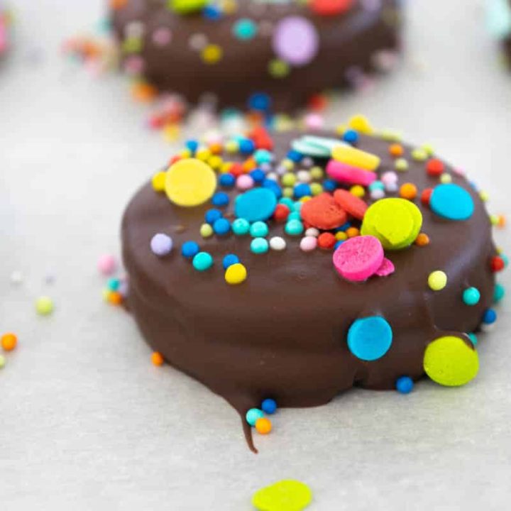 Chocolate Covered Oreos with sprinkles on parchment paper.