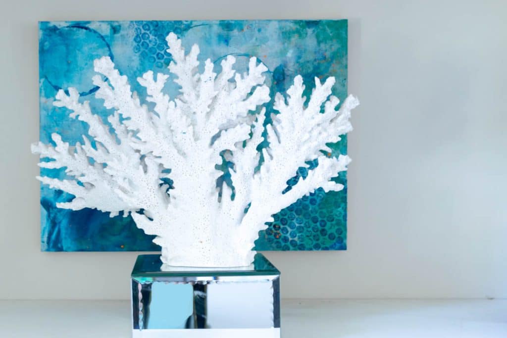 Coral in front of blue abstract painting.