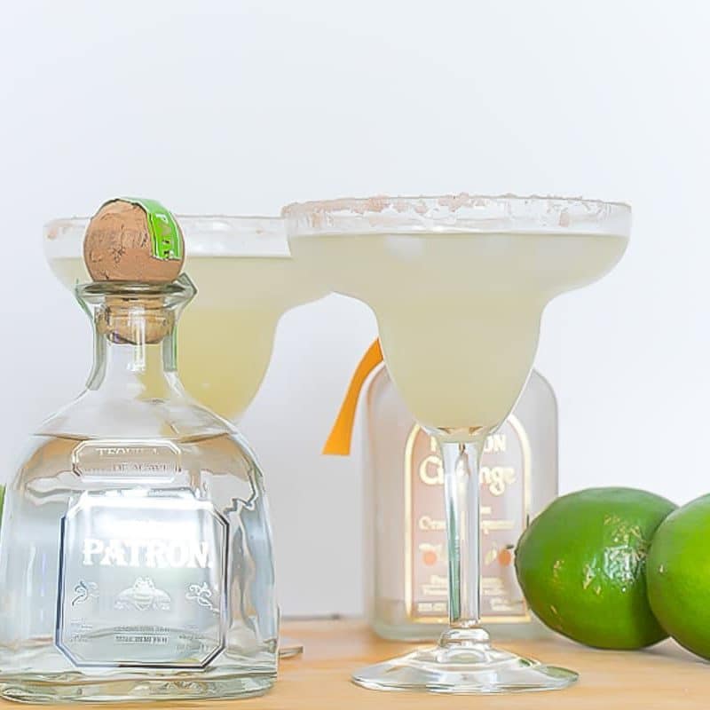 Two Margarita glasses with tequila and limes.