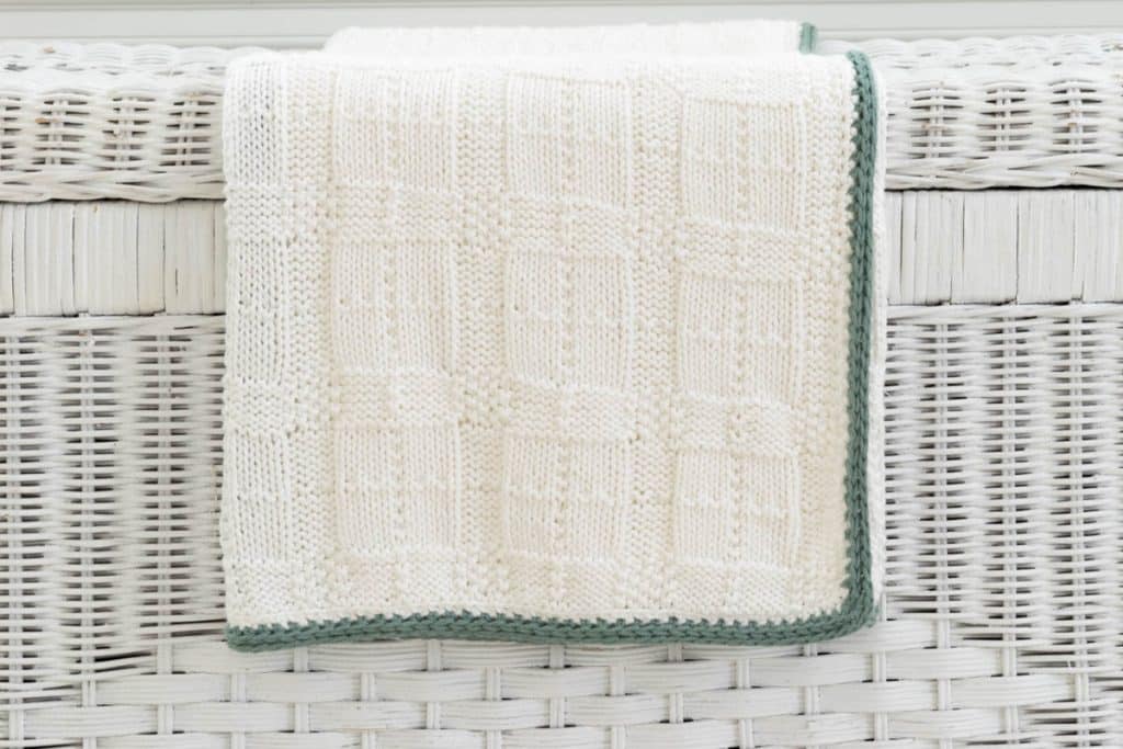 Plaid blanket on white wicker chest.