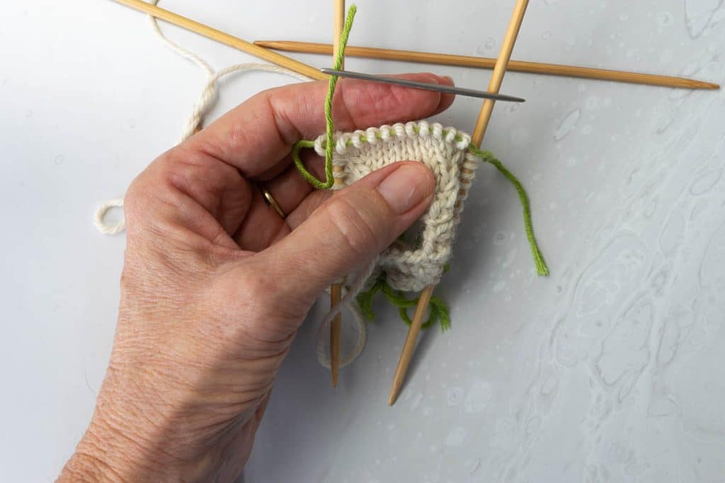 Thread a scrap piece of yarn through the sleeve stitches.