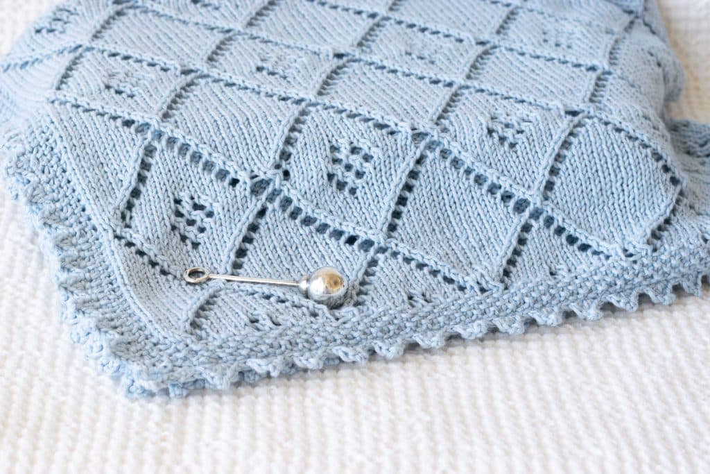 Blue Knit Lace Baby Blanket on White blanket.