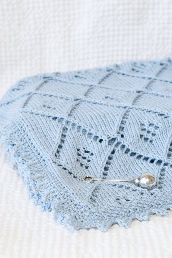Blue Knit Lace Baby Blanket on White blanket.