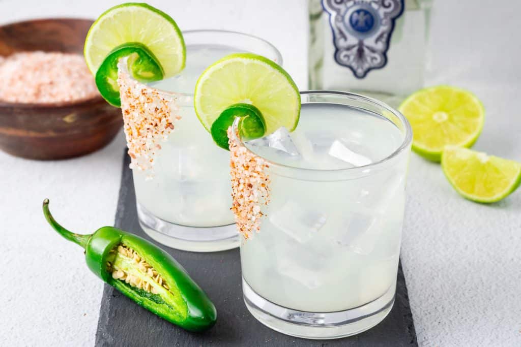 Jalapeño Margarita in a glass iwth a wedge of lime and sliced jalapeno.