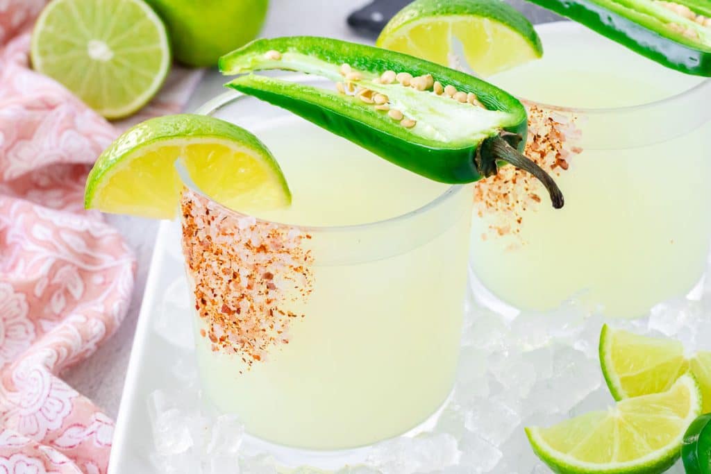 Jalapeño Margarita in a glass iwth a wedge of lime and sliced jalapeno.