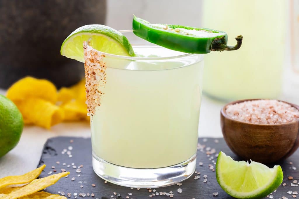 Jalapeño Margarita in a glass iwth a wedge of lime and sliced jalapeno.