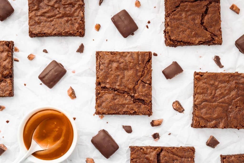 Brownies cut in squares with toffee bits and caramel sauce.