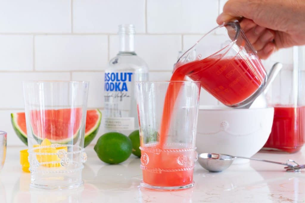 Pouring watermelon juice into a cocktail glass.
