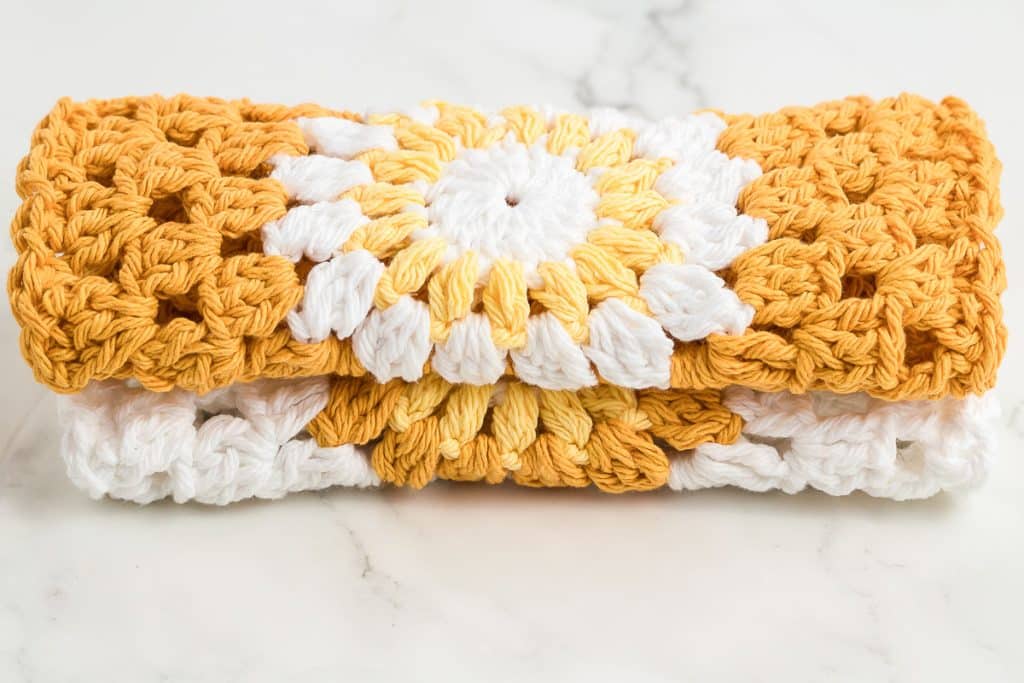 Two folded sunburst crochet dishcloths.