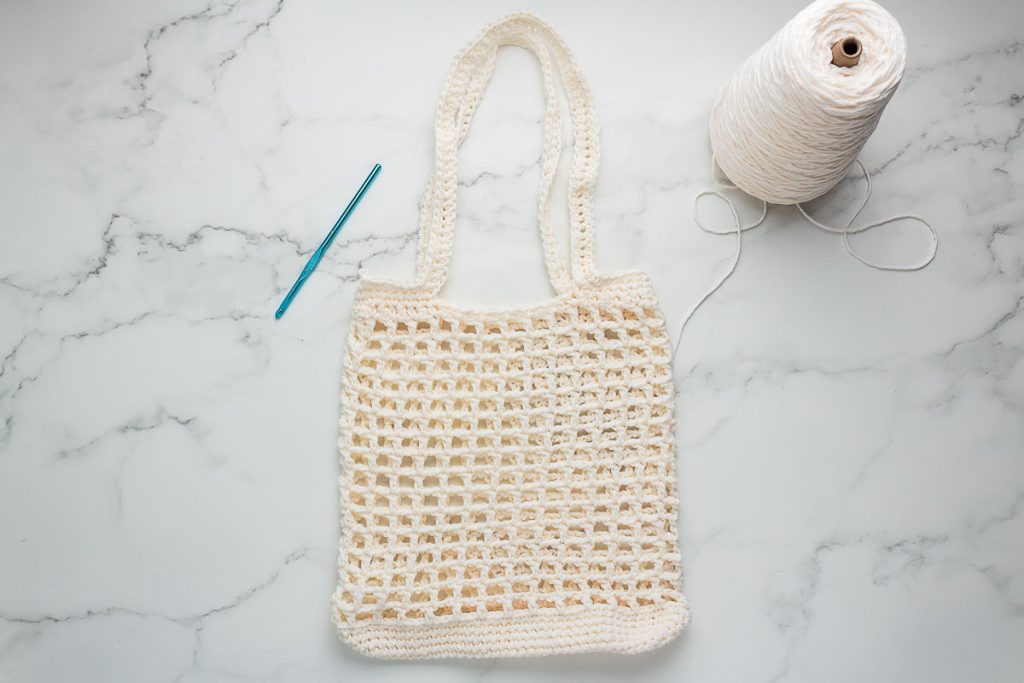 Crochet market bag with yarn and crochet hook.