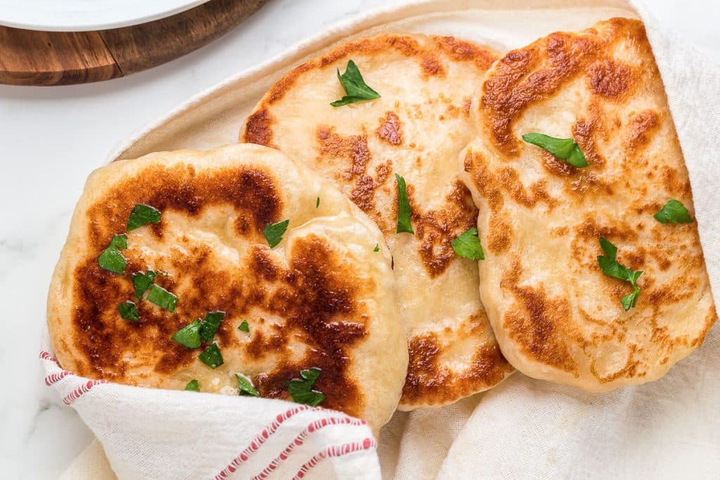 Three sourdough flatbreads wrapped in a towel.