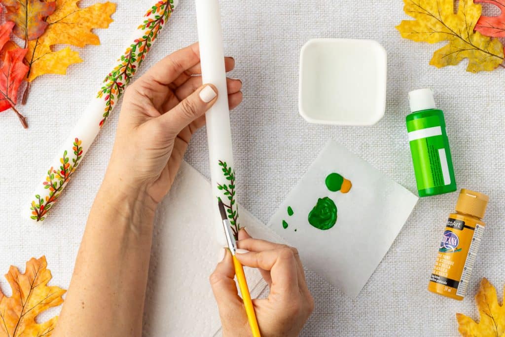 Painting leaves on candle.